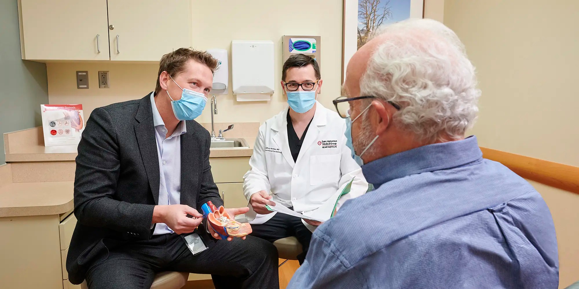 Two doctors sitting in front of a man explaining how the heart works.